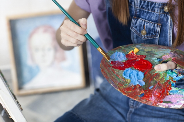 パレットの絵の具を取る女性